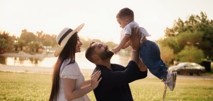 A joyful family moment with parents and child in a sunny park setting.